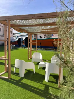 a picnic table and two white chairs under a pergola at Barco - casa con jardín privado frente al mar in Mareny Barraquetas