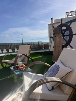 a balcony with a couch and a table with a plate of food at Barco - casa con jardín privado frente al mar in Mareny Barraquetas