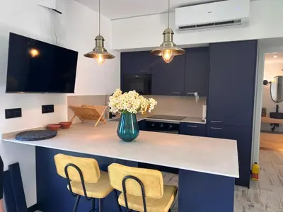 a kitchen with a counter with chairs and a vase of flowers at Barco - casa con jardín privado frente al mar in Mareny Barraquetas