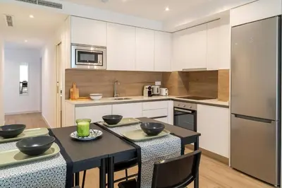 a kitchen with white cabinets and a black table with chairs at Historic Center Apartment in Valencia
