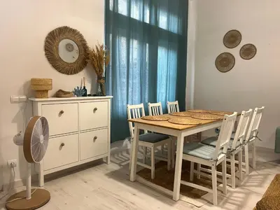 a dining room with a table and chairs and a fan at Casa Playa El Perelló in El Perelló