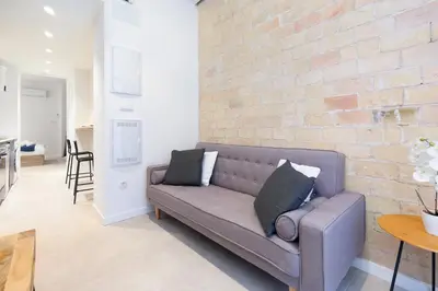 a couch in a living room with a brick wall at My Loft 4 You Democracia I in Valencia