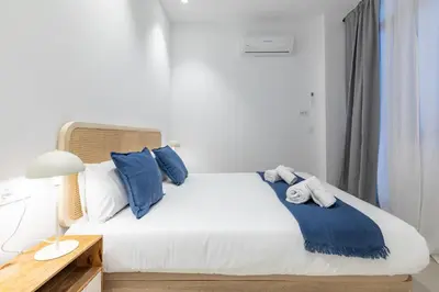 a bedroom with a white bed with blue pillows at My Loft 4 You Democracia I in Valencia