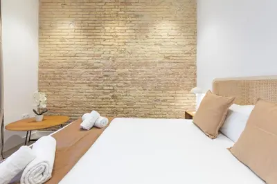 a bedroom with a white bed and a brick wall at My Loft 4 You Democracia II in Valencia