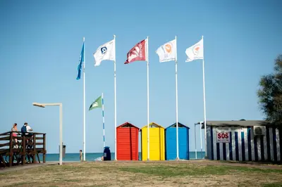 a group of flags on a beach with colorful buildings at Tu rincón frente al mar en Moncofa Ideal para dos in Moncófar