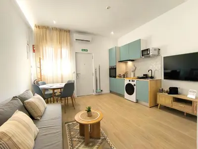 a living room with a couch and a table and a kitchen at The Sunshine Apartment in Valencia