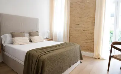 a bedroom with a large white bed and a chair at Valencia Boutique Stays - High End Apartment in Ruzafa for long stays in Valencia