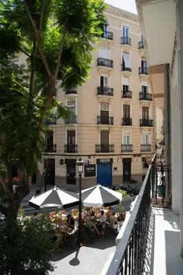 an outdoor patio with tables and umbrellas in front of a building at Valencia Boutique Stays - High End Apartment in Ruzafa for long stays in Valencia