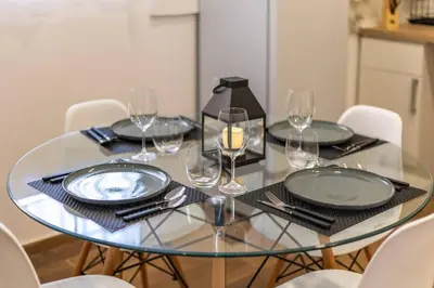 a glass table with plates and wine glasses on it at Estudio tranquilo cerca del Centro in Valencia