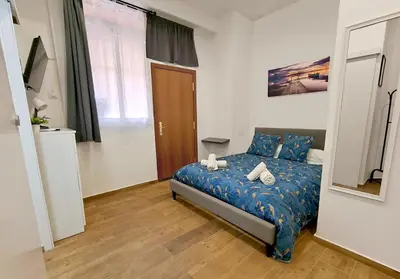 a bedroom with a bed with blue sheets and a mirror at Estudio tranquilo cerca del Centro in Valencia
