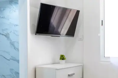 a flat screen tv hanging on a wall above a white cabinet at Estudio tranquilo cerca del Centro in Valencia