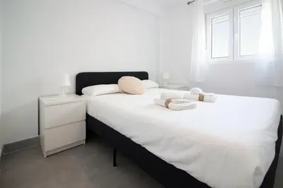 a bedroom with two beds with white sheets and a window at Global Vacacional, Deslumbrante casa en la playa de Sagunto in Sagunto