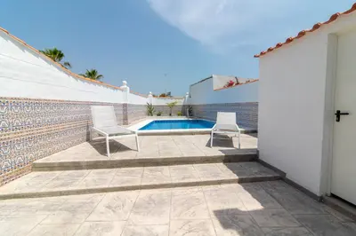 a patio with two chairs and a swimming pool at Global Vacacional, Deslumbrante casa en la playa de Sagunto in Sagunto