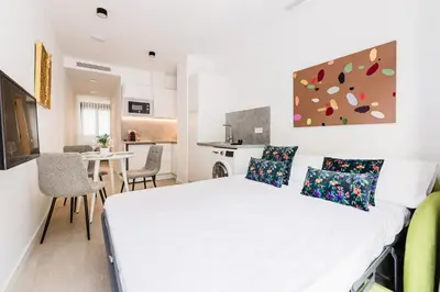 a bedroom with a white bed and a kitchen at Fantastico Apartamento en Valencia in Valencia