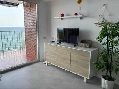 a living room with a television and a balcony at Vista al mar con piscina in Faro de Cullera