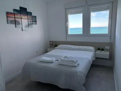 a white bedroom with a bed with towels on it at Vista al mar con piscina in Faro de Cullera