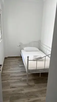 a white bed in a room with a wooden floor at Apartamento acogedor playa Cullera in Cullera