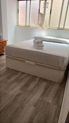 a bed in a room with a wooden floor at Apartamento acogedor playa Cullera in Cullera