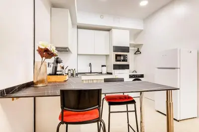 a kitchen with a large counter with two chairs at Torrefiel Charm Apartment in Valencia