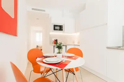 a dining room with a white table and orange chairs at Fantastico apartamento en Valencia in Valencia