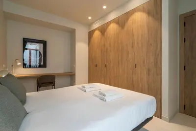 a bedroom with a white bed and a wooden cabinet at VLC Host - Martí Apartments in Valencia