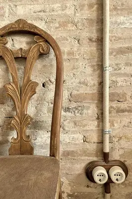 a wooden chair next to a brick wall with a pipe at Casa Juana in Valencia