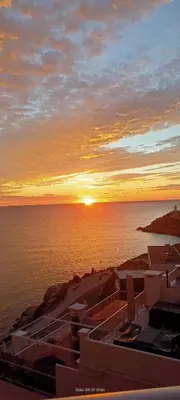 a sunset over the ocean with buildings and the water at APARTAMENTO Claudia FARO in Faro de Cullera