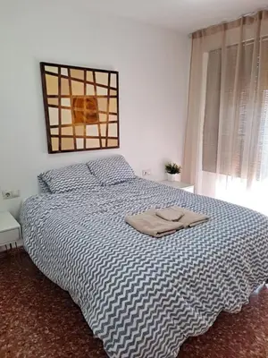 a bedroom with a bed with a blue and white comforter at APARTAMENTO COMODO FERIA dE VALENCIA in Valencia