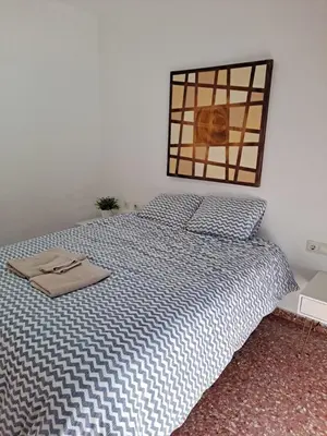 a bed with a blue and white comforter in a bedroom at APARTAMENTO COMODO FERIA dE VALENCIA in Valencia