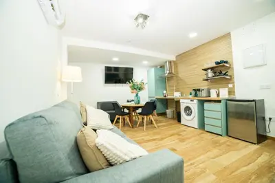 a living room with a blue couch and a kitchen at Playa Las Arenas 2 Apartamento in Valencia