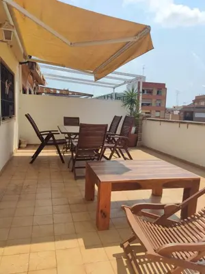 a patio with chairs and tables on a roof at fully-equipped luxury penthouse in Almácera