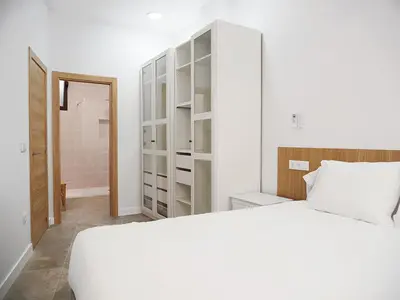 a bedroom with a white bed and a closet at Apartamentos SAN JOSÉ in El Puig