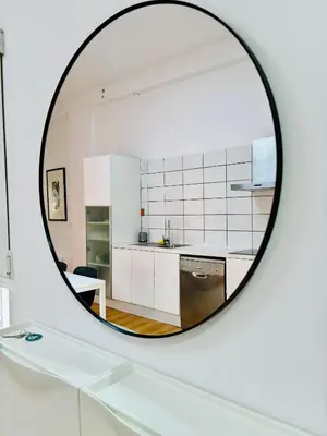 a mirror reflecting a kitchen with white cabinets at Reina loft in Valencia