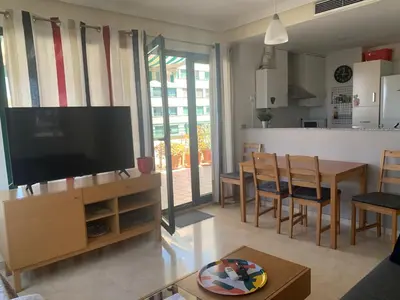 a living room with a television and a dining room at Atico Ciudad de las Ciencias Terraza y parking in Valencia