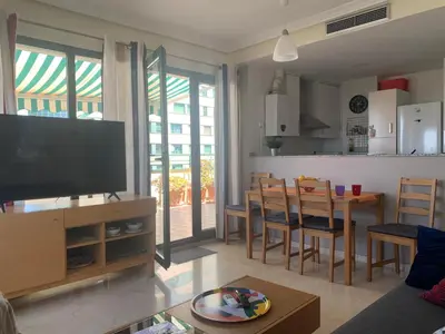 a living room with a television and a table with chairs at Atico Ciudad de las Ciencias Terraza y parking in Valencia