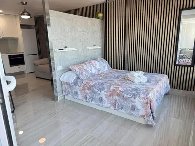 a living room with a couch and a kitchen at Suite Miramar primera línea playa in Cullera