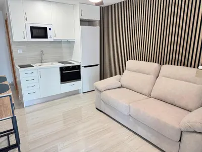 a kitchen with a table and a tv on a wall at Suite Miramar primera línea playa in Cullera