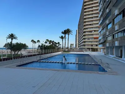 a large swimming pool next to a tall building at Suite Miramar primera línea playa in Cullera