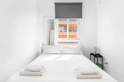 a white bedroom with a bed with two towels on it at GuestReady - Comfort in Valencia in Valencia