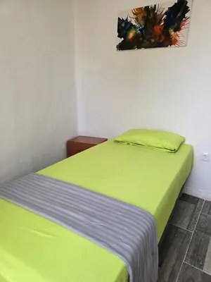 a bedroom with a bed with green sheets at Habitaciones La Estación in Algemesí