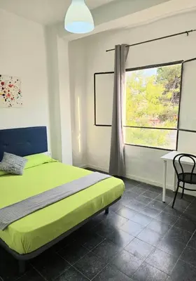 a bedroom with a green bed and a window at Habitaciones La Estación in Algemesí
