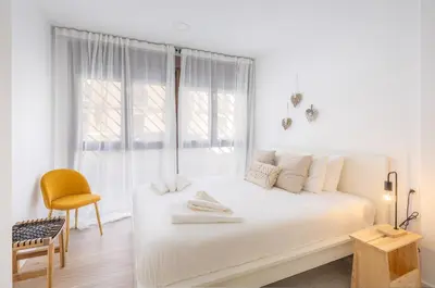 a white bedroom with a white bed and a chair at VL - Casa Girasol in Valencia