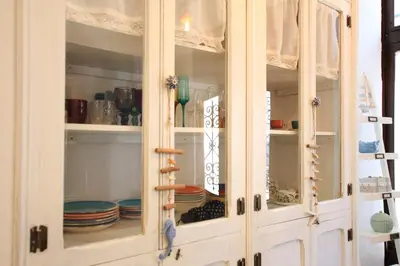 a white cabinet with dishes inside of it at Modernist house in Cabanyal in Valencia