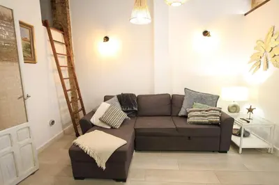 a living room with a brown couch and a ladder at Modernist house in Cabanyal in Valencia