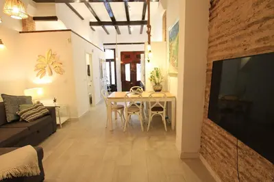 a living room with a dining room table and a television at Modernist house in Cabanyal in Valencia