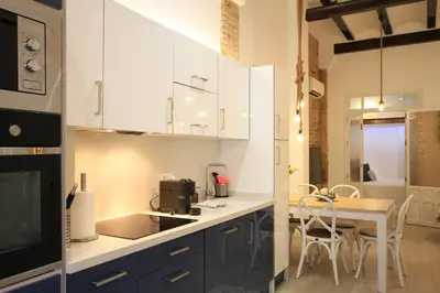 a kitchen with white cabinets and a table with chairs at Modernist house in Cabanyal in Valencia