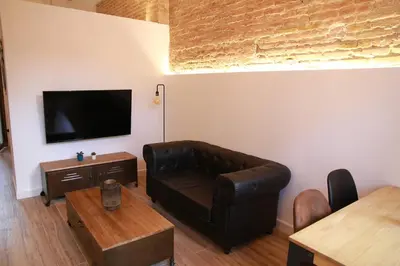 a living room with a leather couch and a flat screen tv at Grandma's fishermen's house in Cabanyal in Valencia