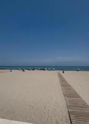 a sandy beach with a wooden boardwalk and the ocean at 1st Line Beach Direct Access Private Parking in Valencia