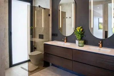 a bathroom with two sinks and a toilet and mirrors at Villa Praya in Valencia in Bétera