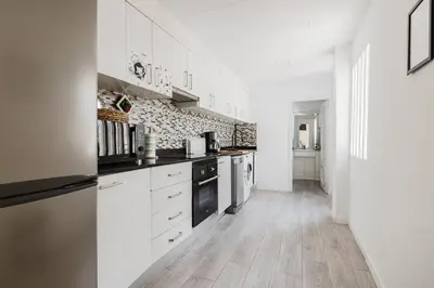 a kitchen with white cabinets and black appliances at Hogar con encanto a 10 min del centro de Valencia in Valencia